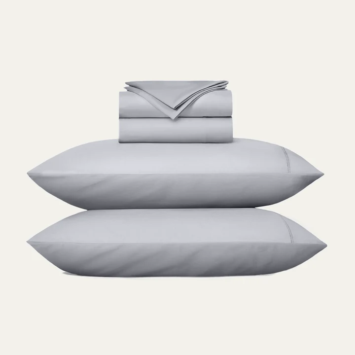 Stacked gray pillows and folded Miracle Made sheets